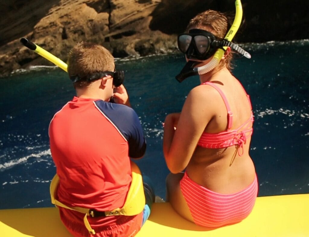 a boy and girl in swimsuits and snorkels on a boat